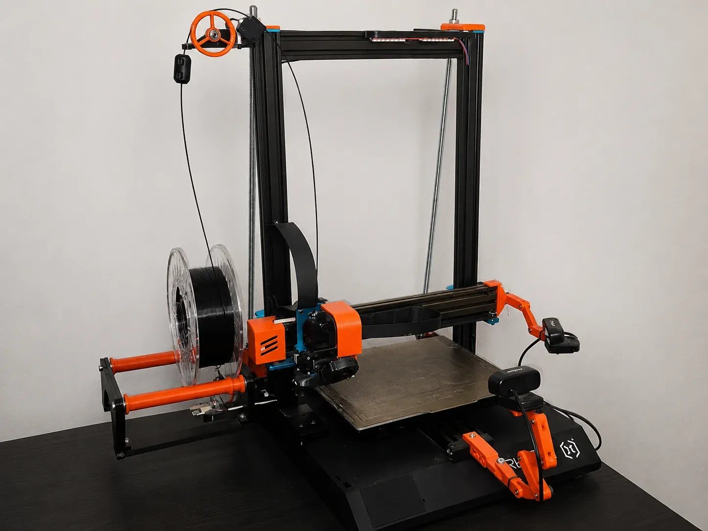 Modified Artillery Sidewinder X1 3D printer on a workshop bench, with a black filament spool on a holder featuring a weight sensor module and a magnetic build plate.